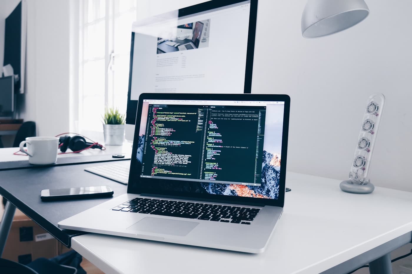 Arbeitsplatz mit Laptop und Programmcode auf dem Bildschirm